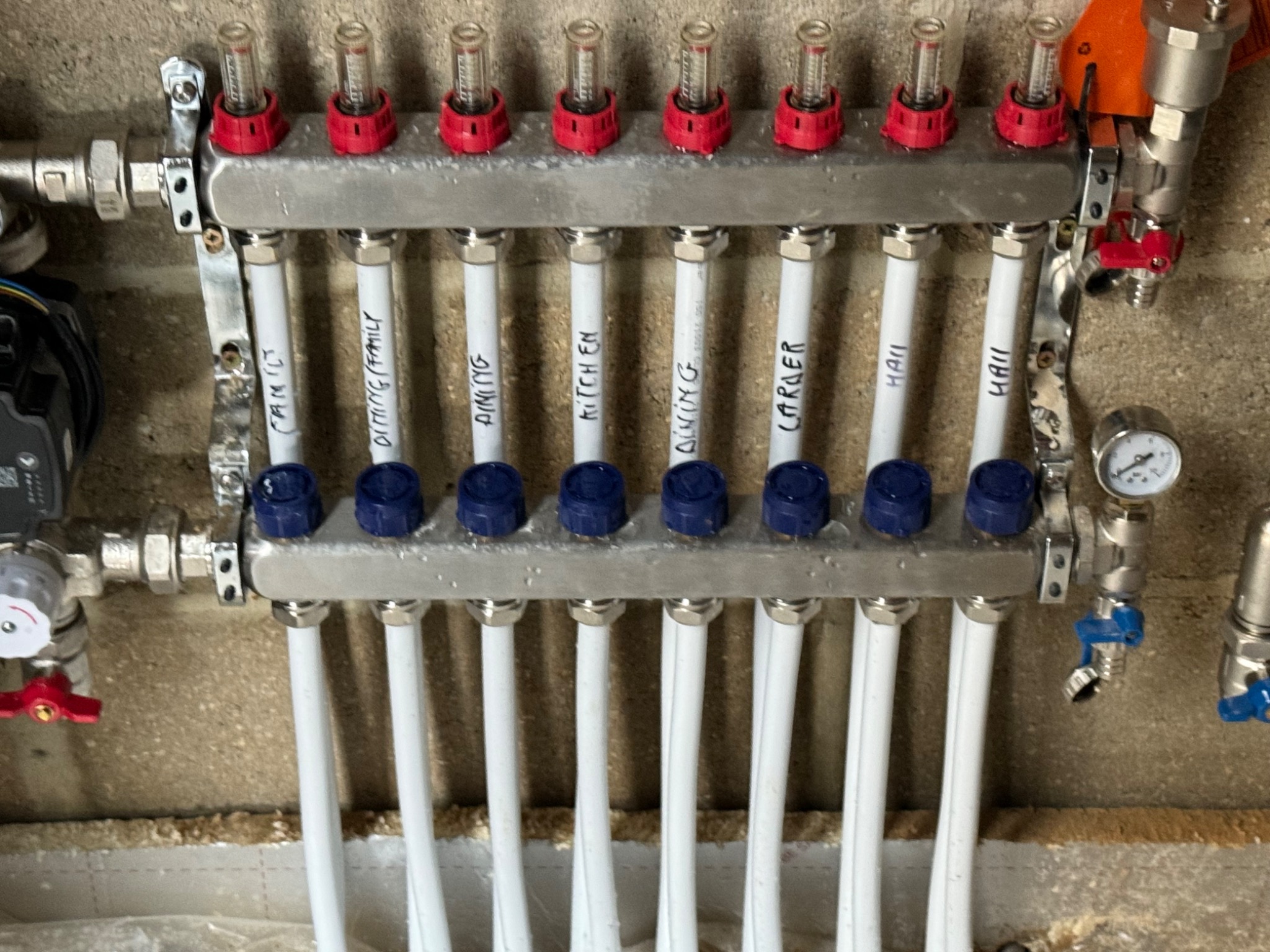 Close-up of underfloor heating manifold flow meters and labelled circuits
