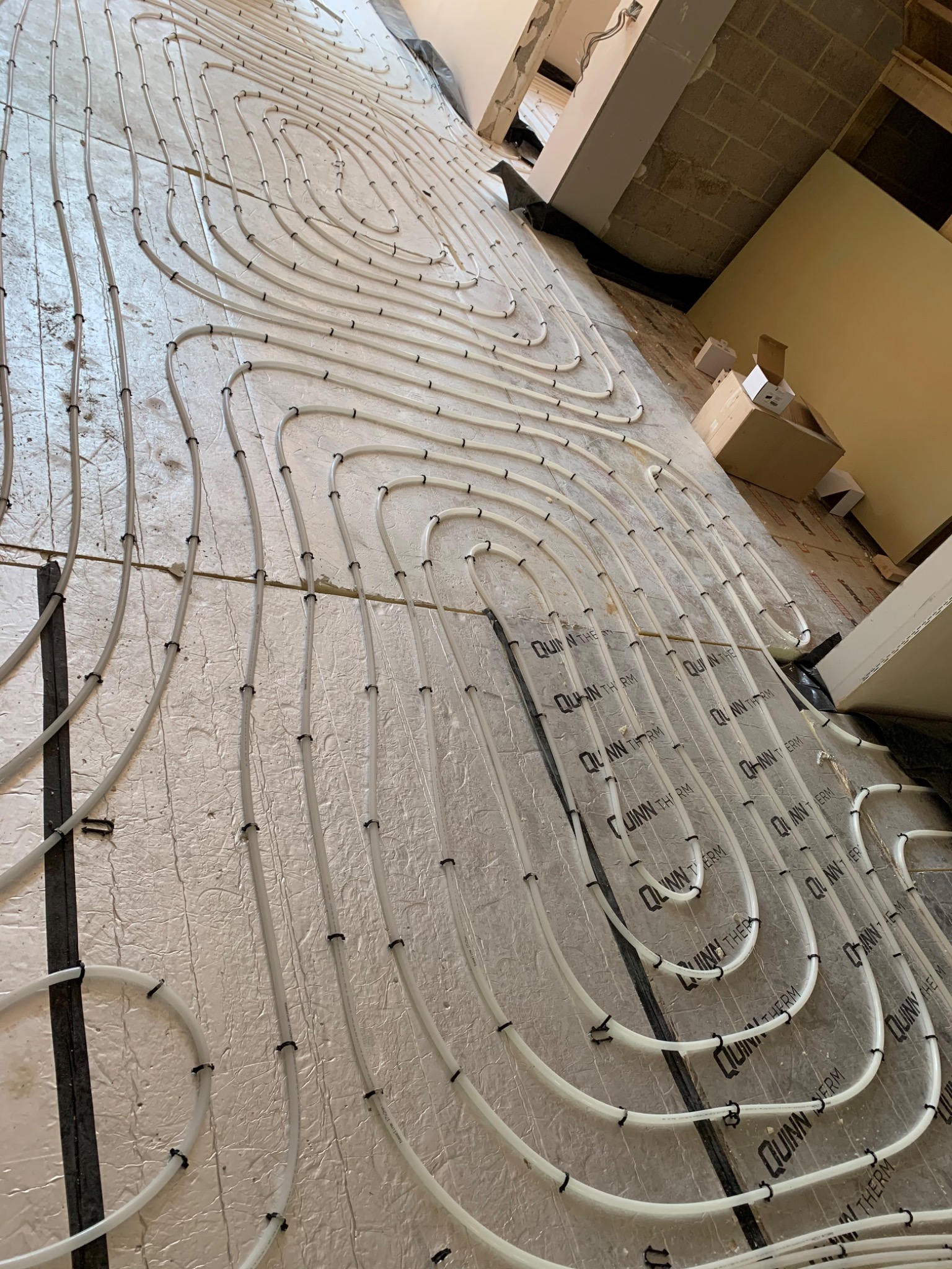 White underfloor heating pipe loops installed over insulation in a refurbishment