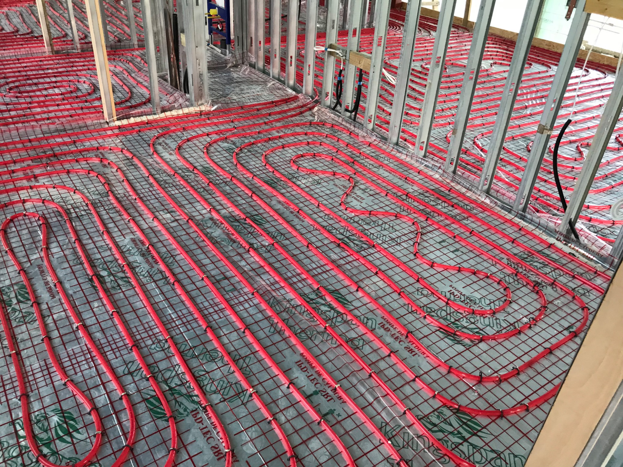 Red underfloor heating loops covering a steel-framed floor plate