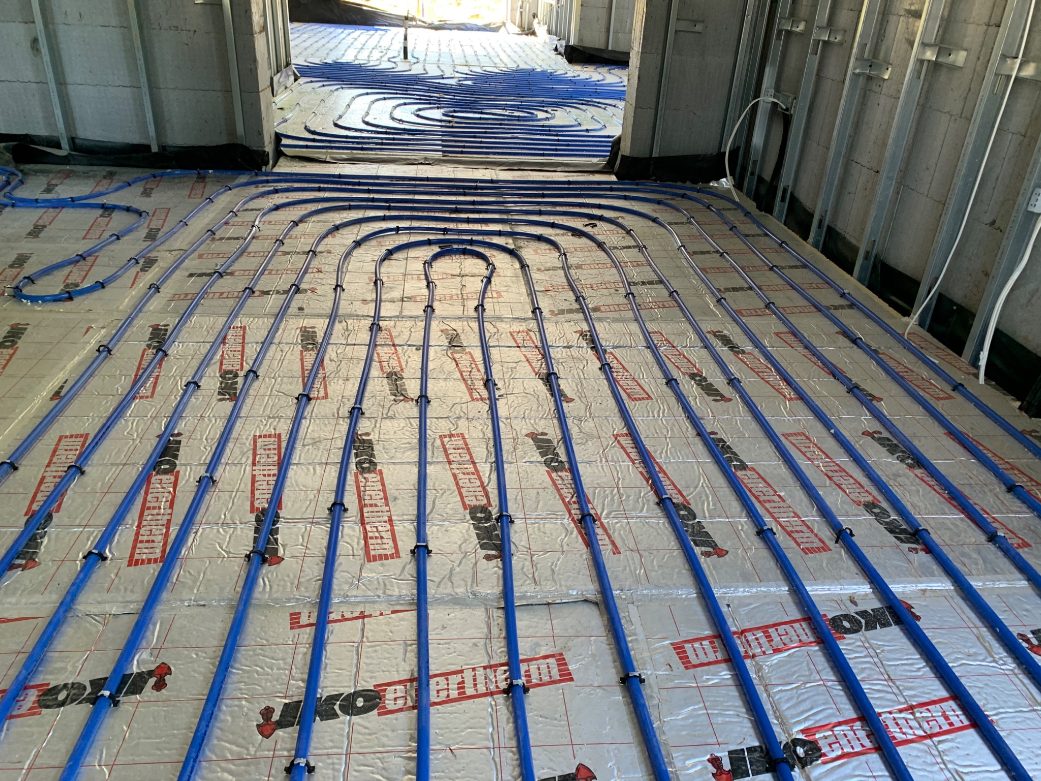 Blue underfloor heating pipes laid at even spacing over foil-faced insulation