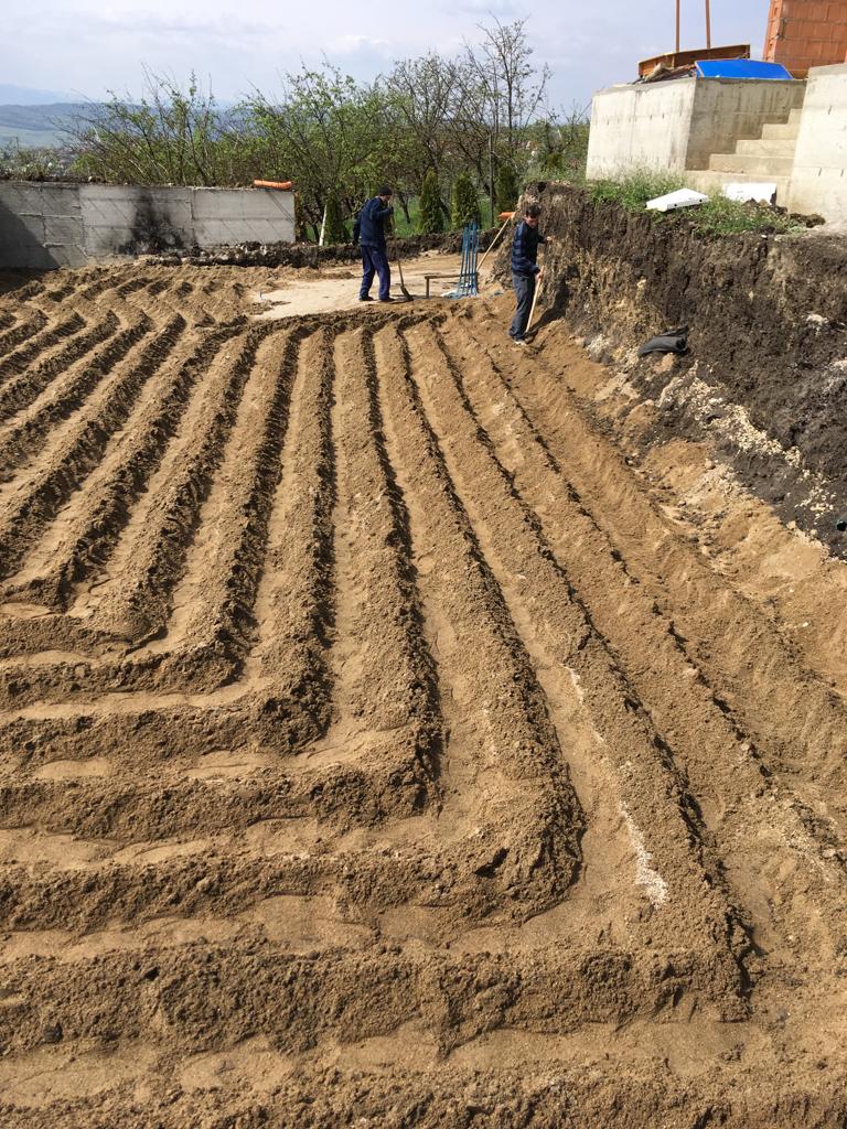 Excavated ground area prepared with trenches for horizontal ground collectors