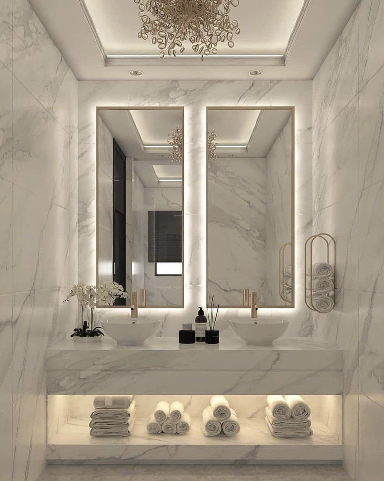 Marble powder room with backlit mirrors and twin vessel basins