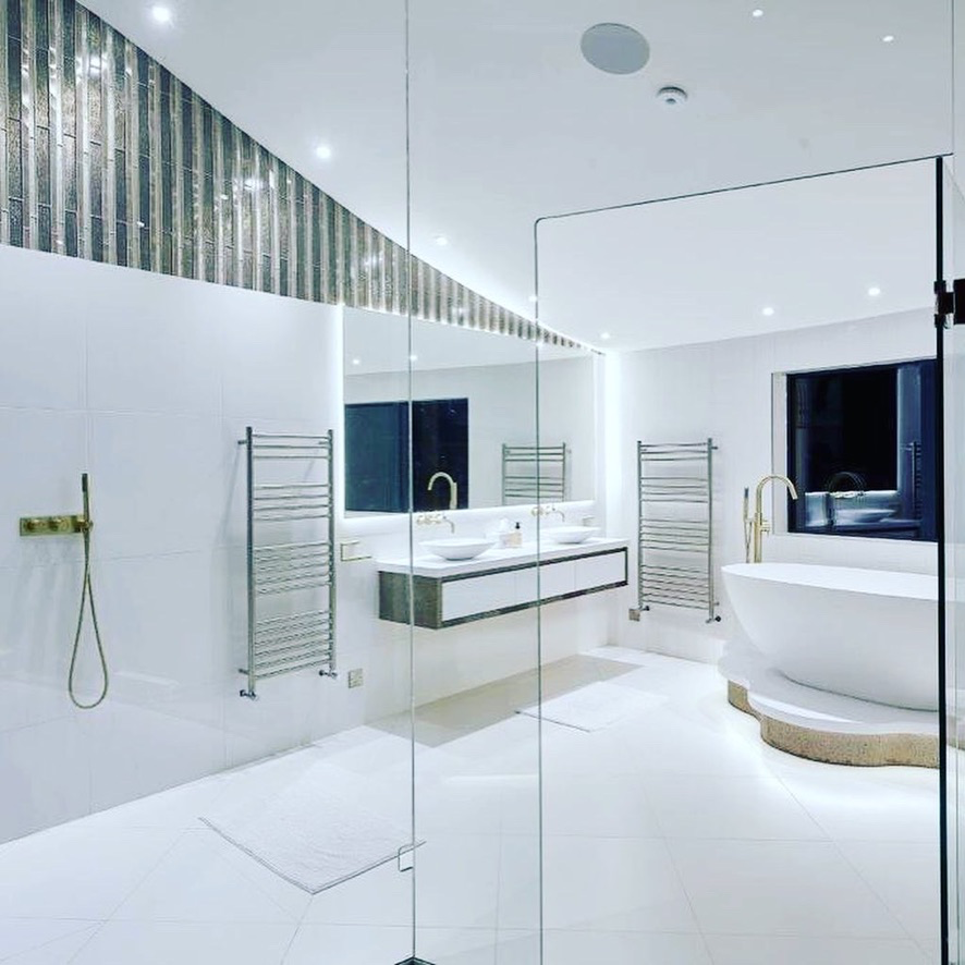 White principal bathroom with twin basins, freestanding bath and heated towel rails