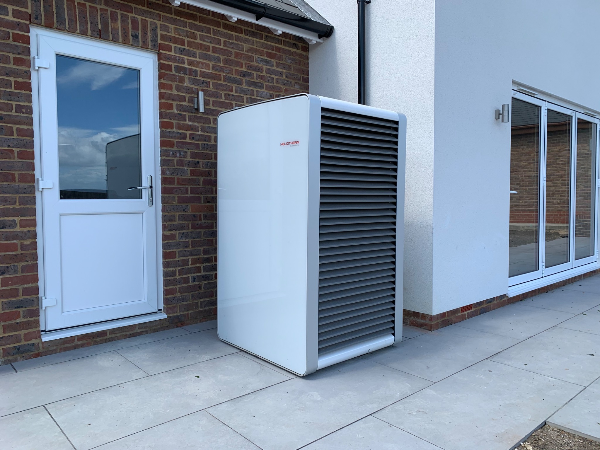 Heliotherm air source heat pump installed beside a contemporary residential extension.