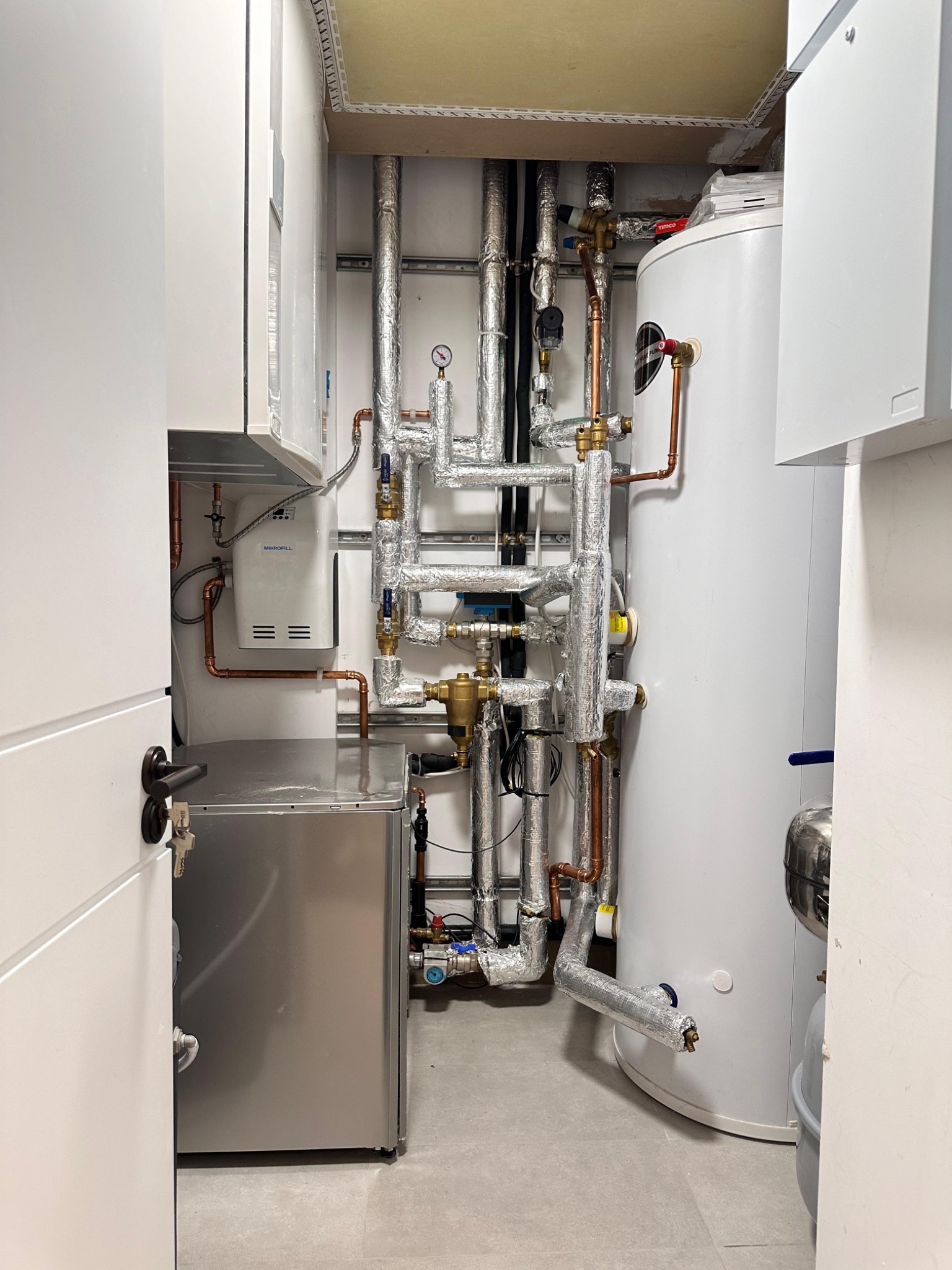 Compact plant cupboard with insulated pipework and an unvented hot water cylinder