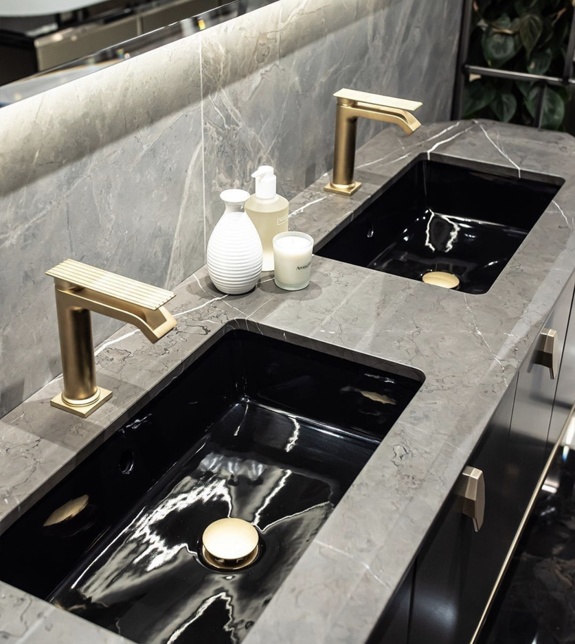 Stone vanity top with twin undermount basins and brushed brass mixers