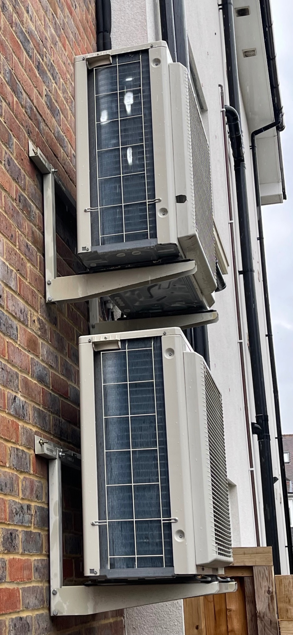 Compact wall-mounted outdoor condenser arrangement with protected pipework.