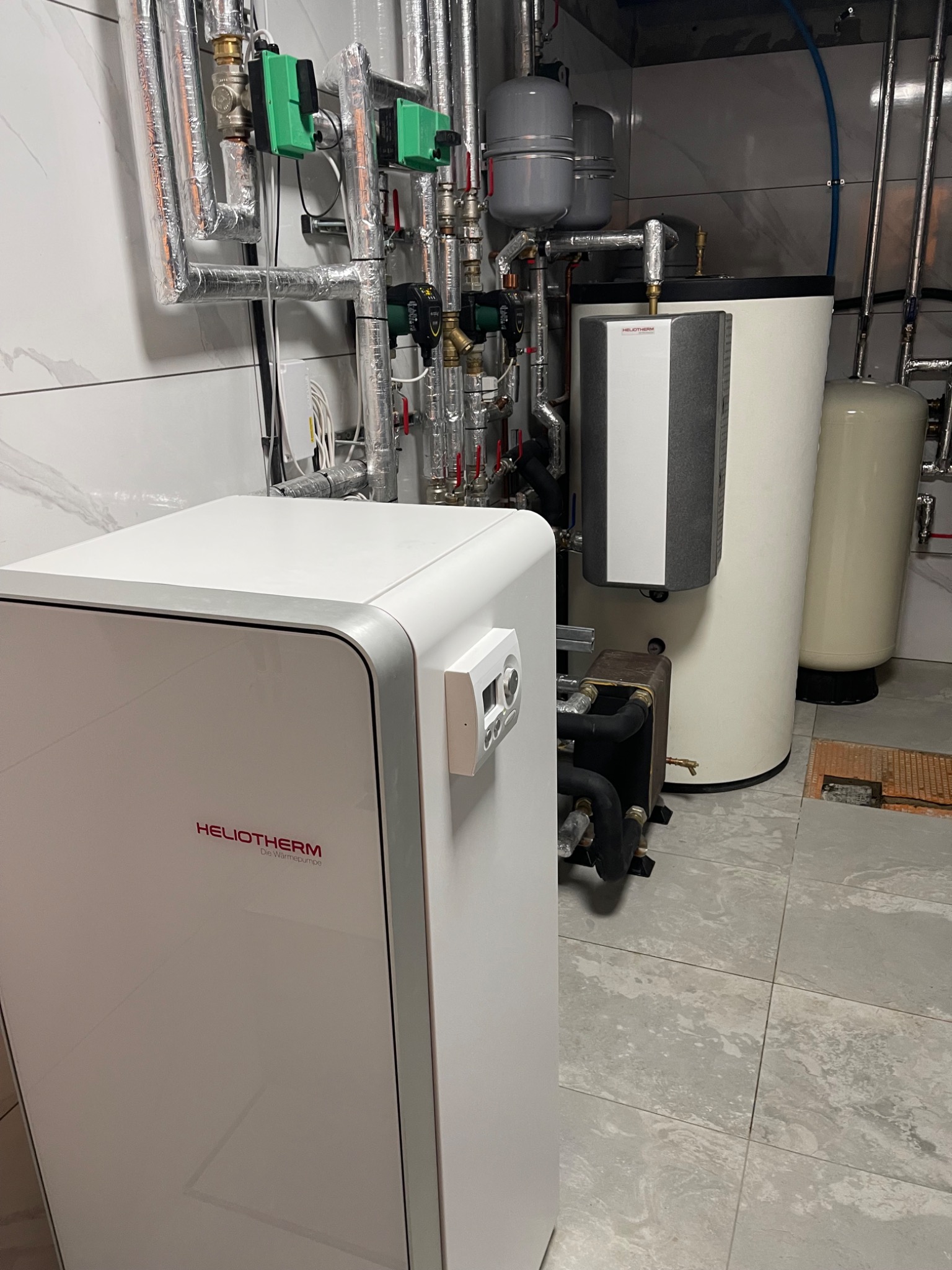 Ground source heat pump hydraulic installation with buffer storage, circulation pumps and controls.