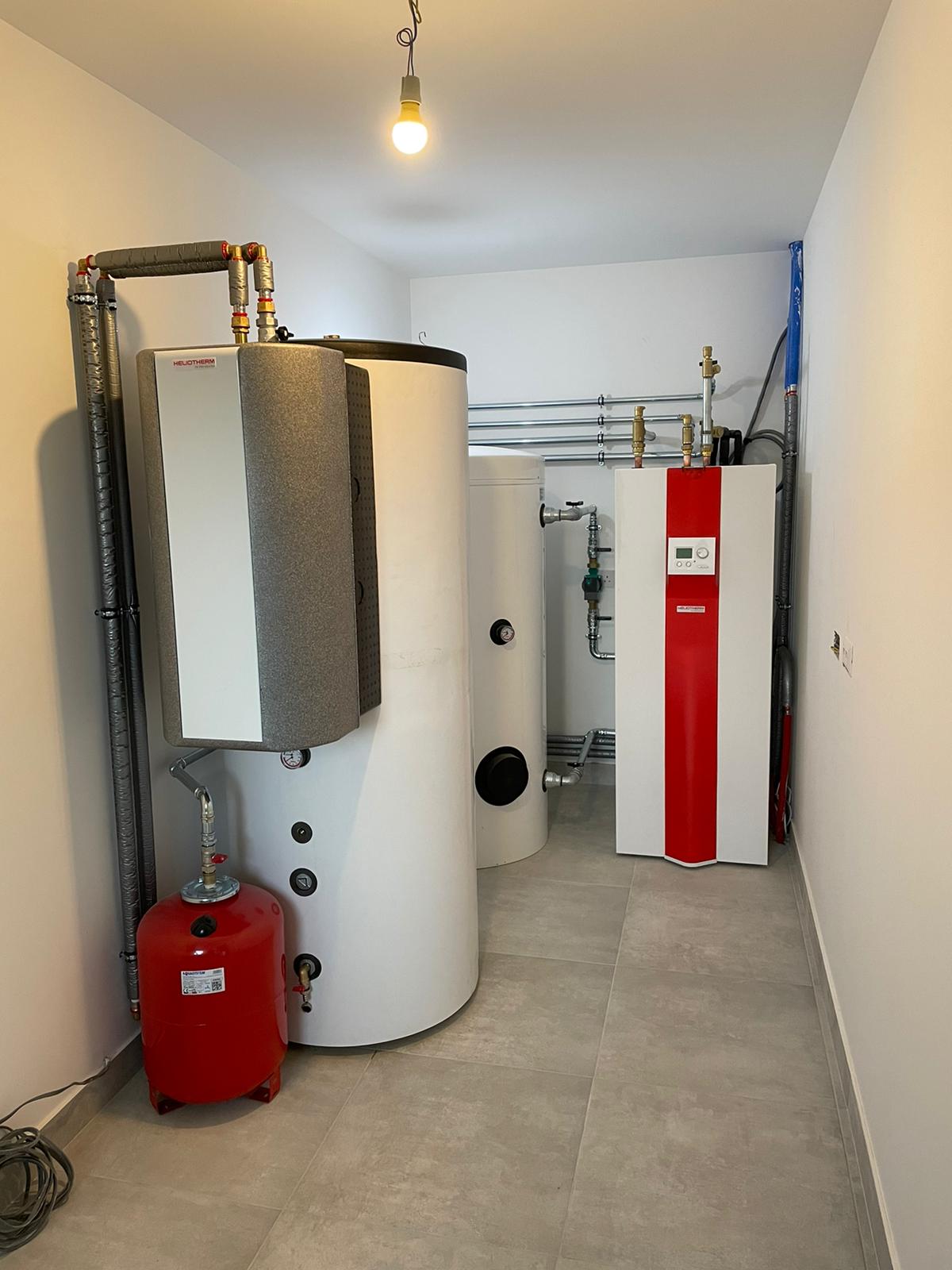 Compact Heliotherm ground source heat pump installation with thermal stores and expansion vessel.