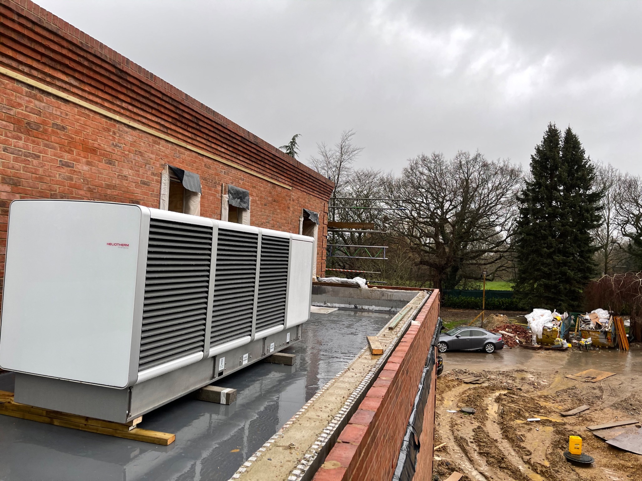 Heliotherm air source heat pump installed on a prepared roof-level platform.