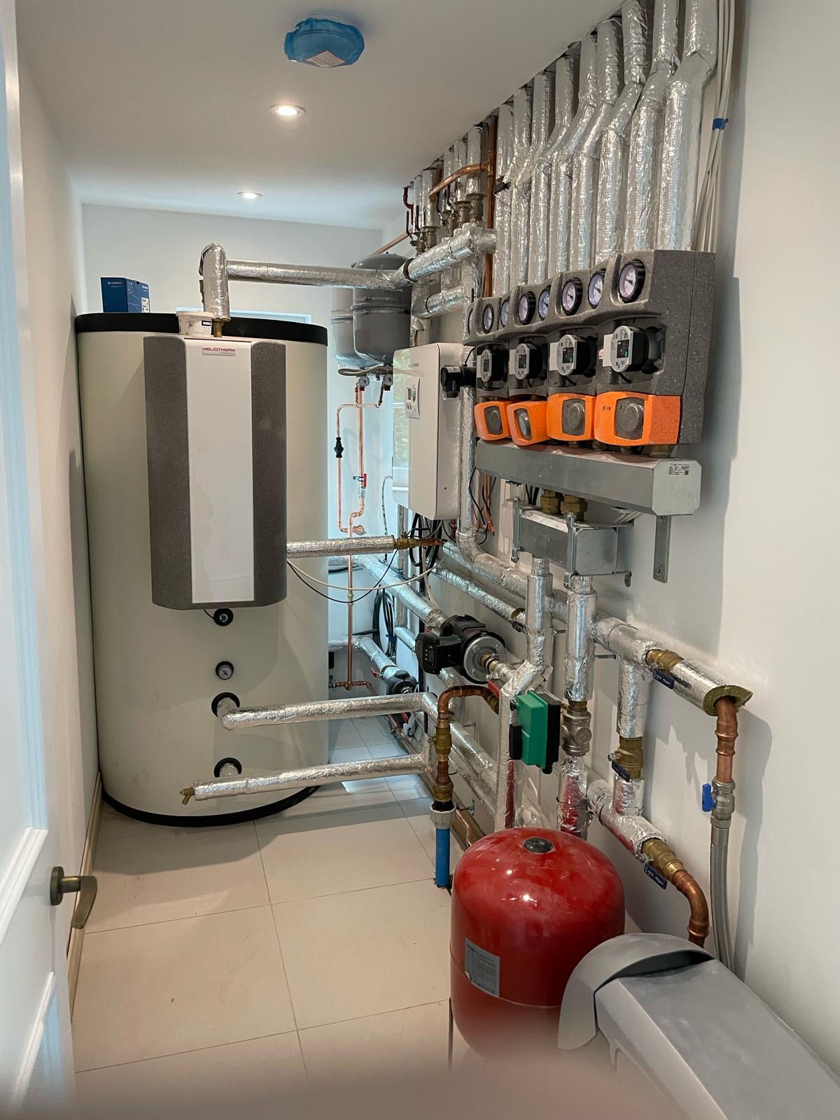 Narrow plant room with Heliotherm cylinder and wall-mounted pump groups