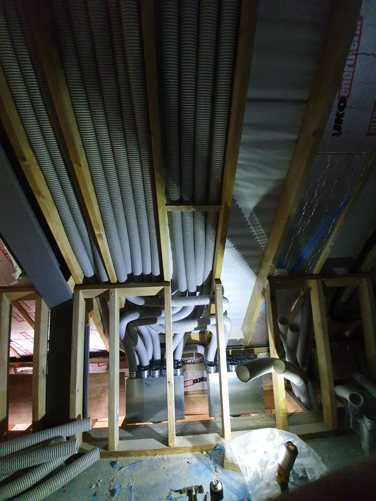 Radial MVHR ductwork routed through a timber-framed loft