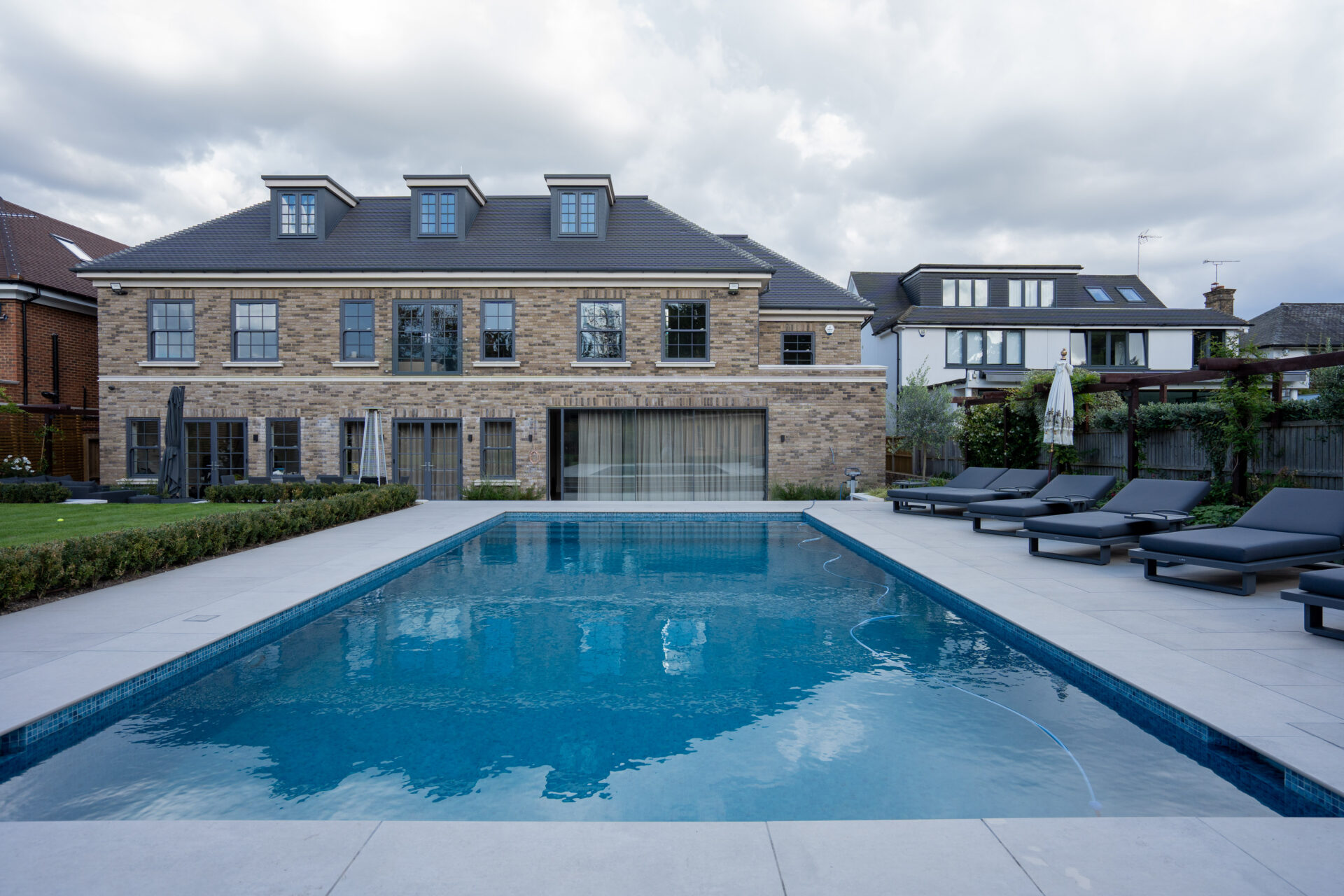 Outdoor residential swimming pool alongside a brick-built house
