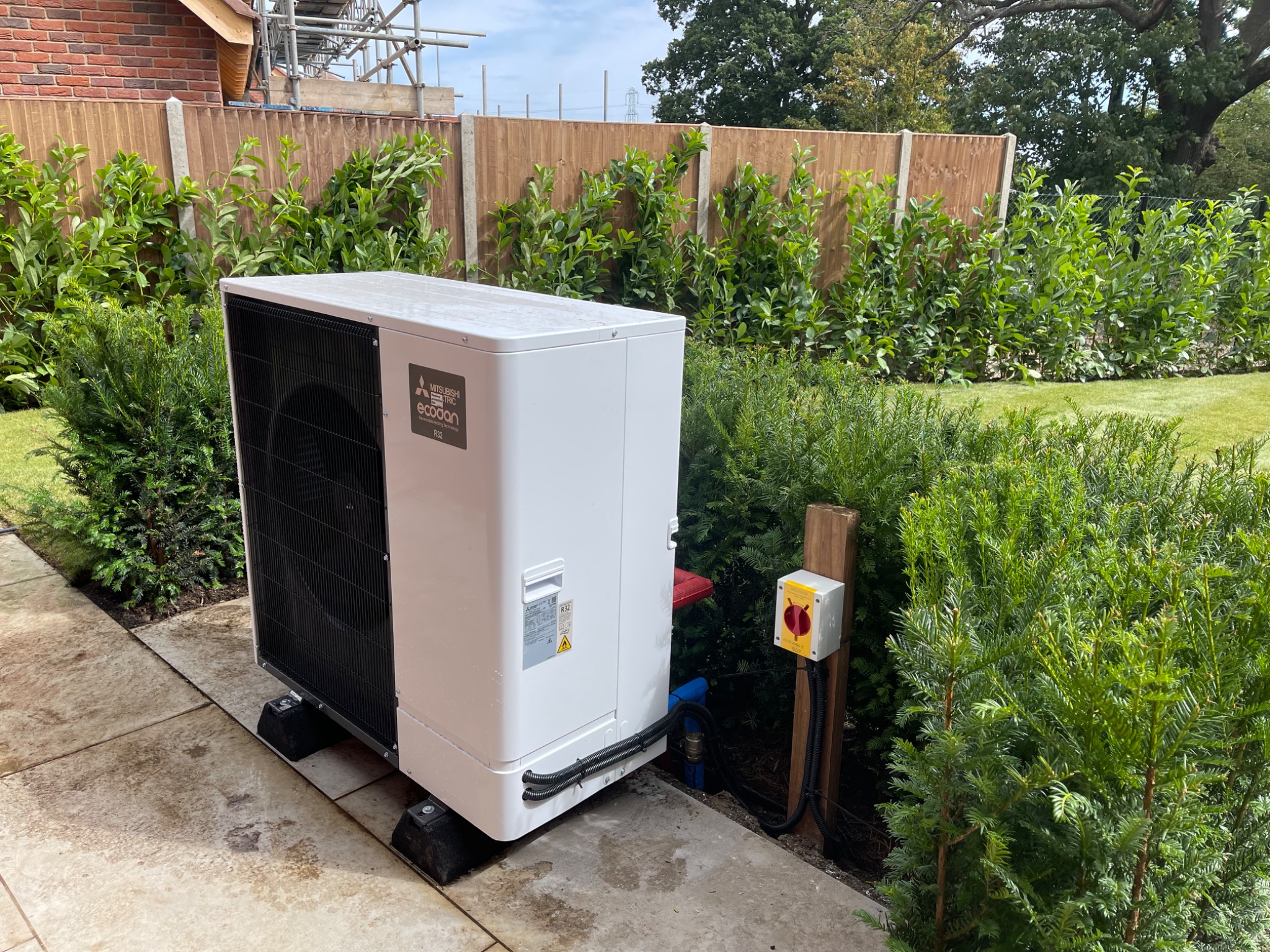 Mitsubishi Electric Ecodan air source heat pump installed beside landscaped planting.