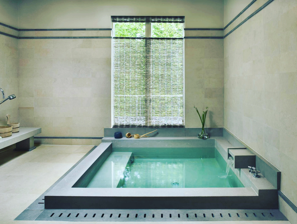 Sunken indoor spa pool with stone surround and integrated water feature