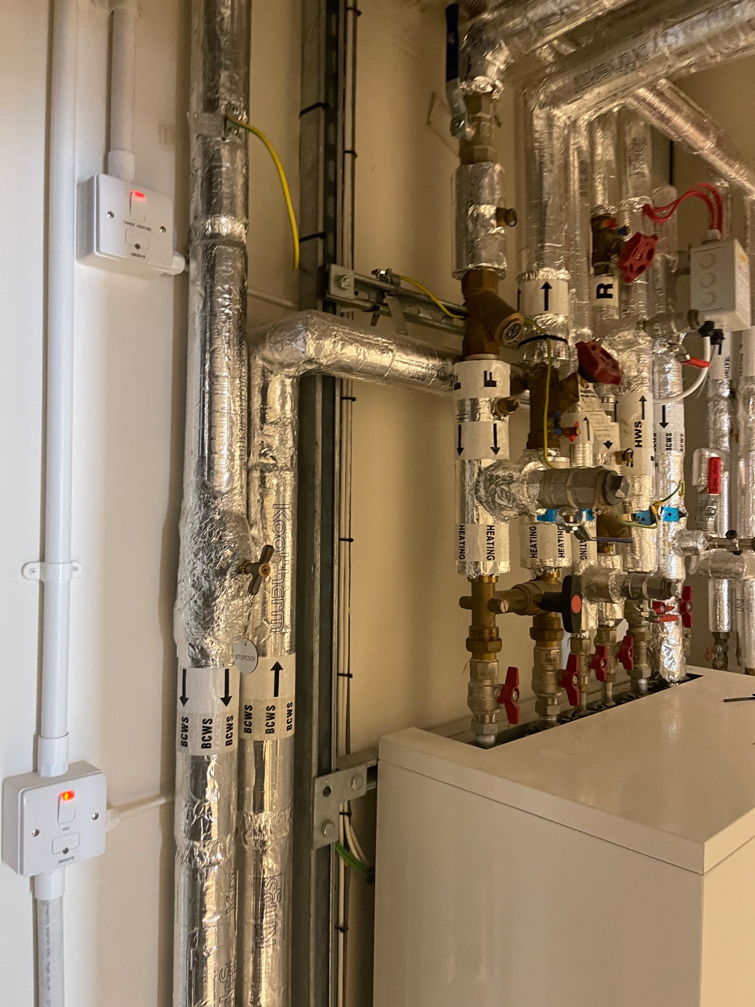 Insulated risers labelled HEATING, HWS and BCWS with brass isolation valves