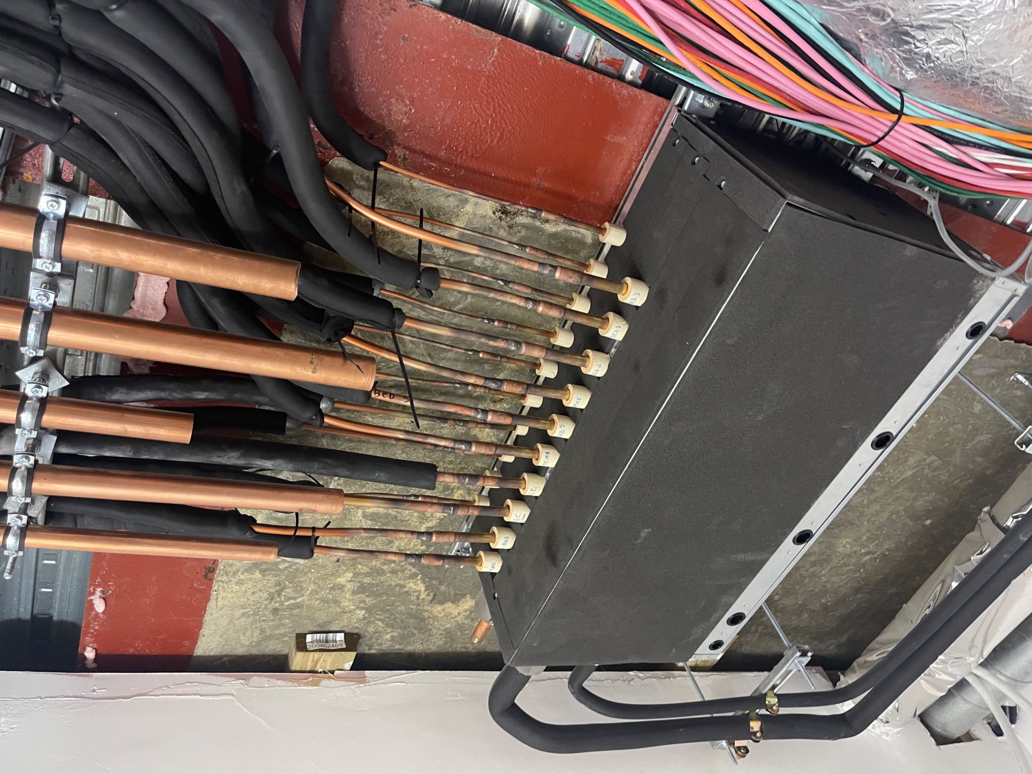 Concealed indoor air-conditioning unit with insulated refrigerant pipework and branch connections.