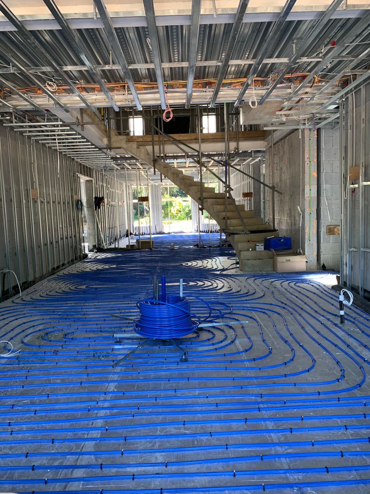 Blue underfloor heating pipework installed across a ground floor under construction