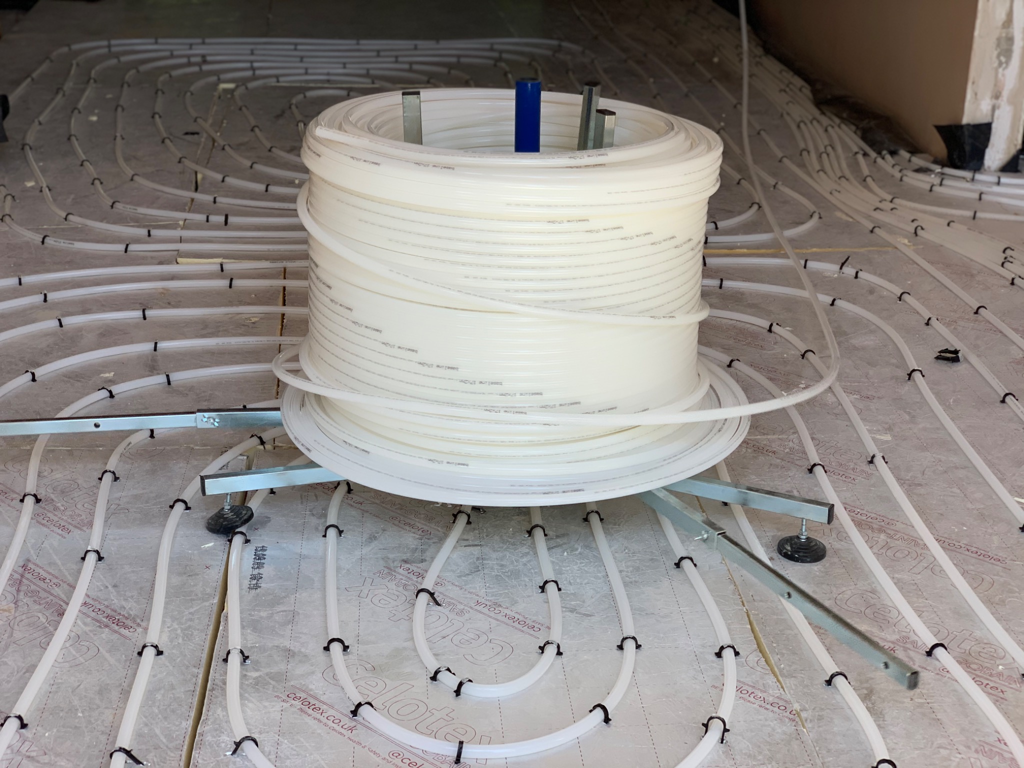 Pipe decoiler with coil of underfloor heating pipe on insulation boards