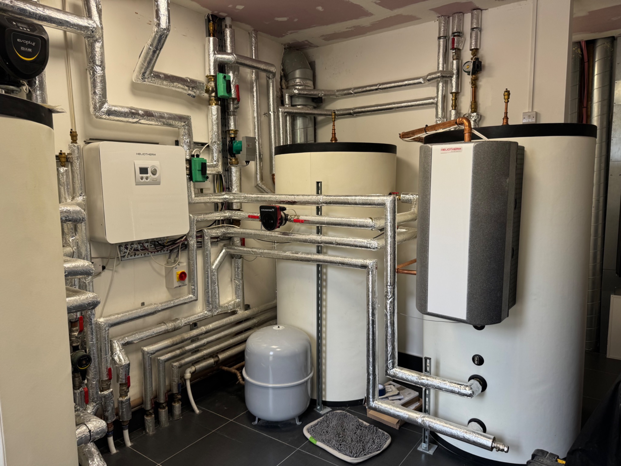 Wide view of a plant room with Heliotherm units, cylinders and insulated pipework
