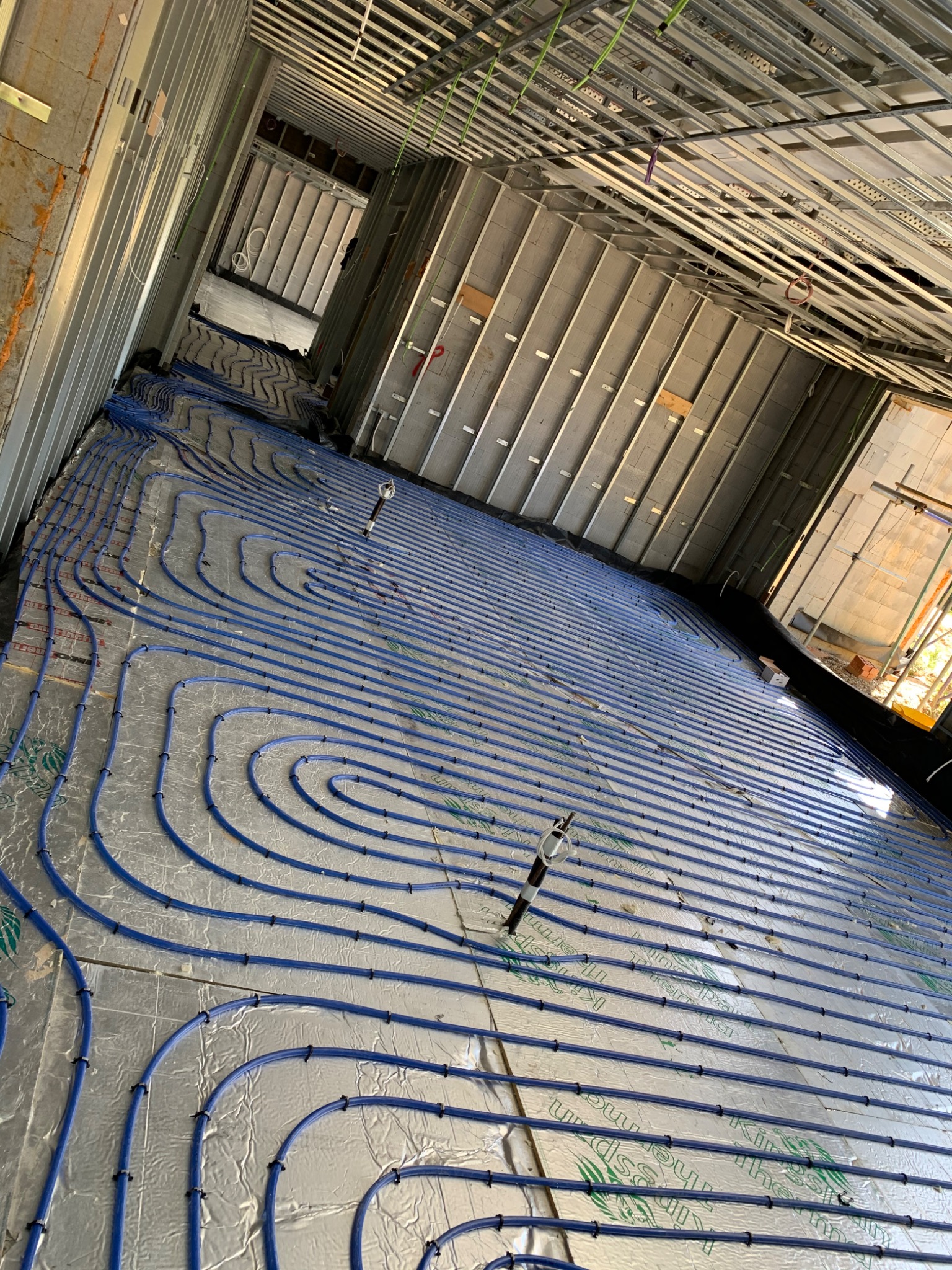 Underfloor heating circuits routed through rooms of a building under construction