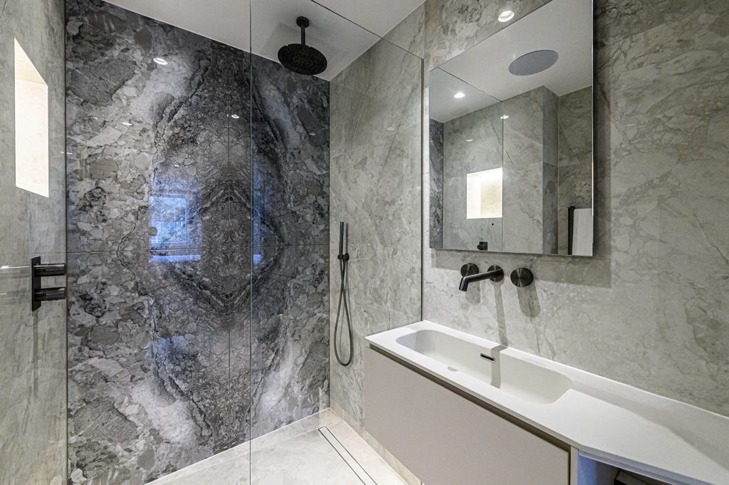 Compact shower room with book-matched marble feature wall and matt black brassware
